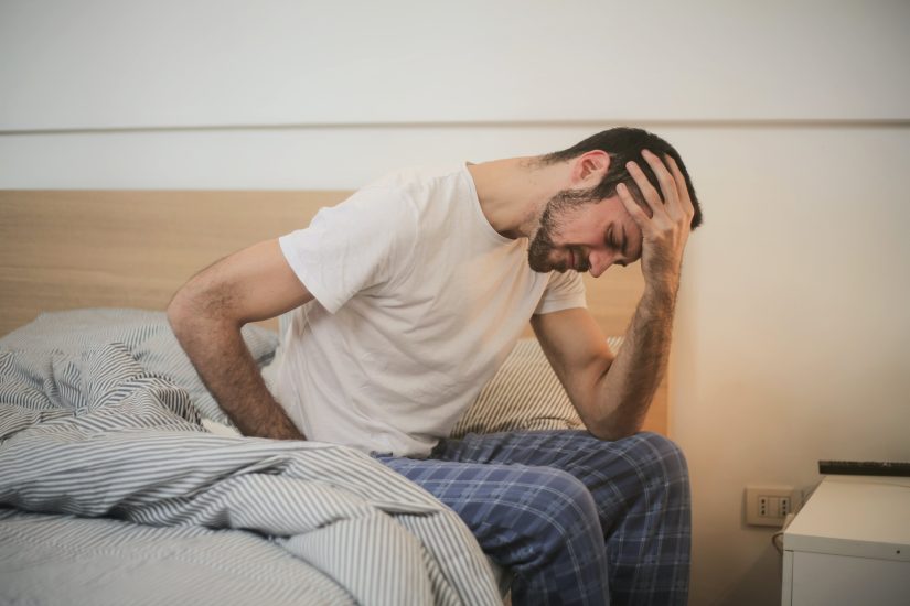 Man with chronic back pain getting out of bed. 